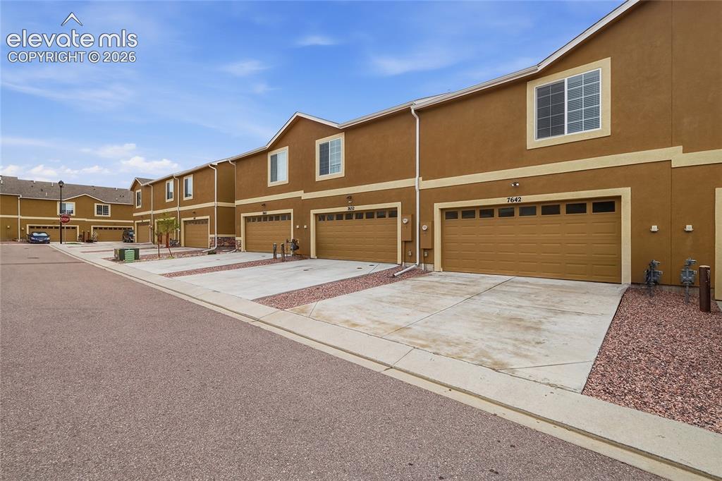 Image 33 of 44: Row of townhomes featuring warm earth-toned stucco exteriors with light tri