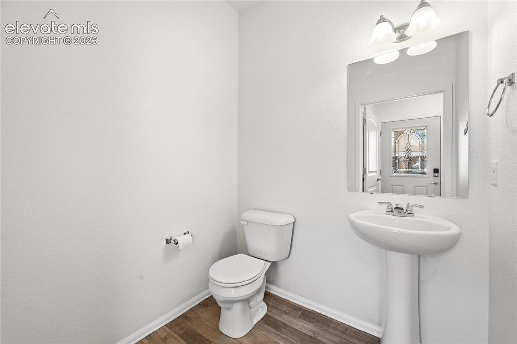 Image 7 of 44: Powder room featuring a pedestal sink, white toilet, wall-mounted mirror, a