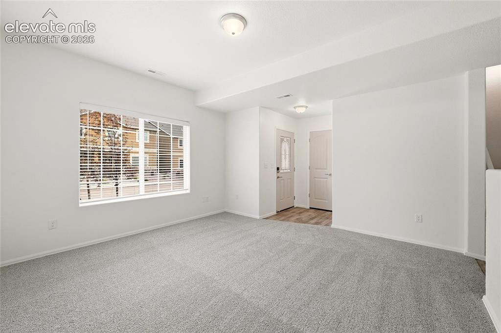 Image 8 of 44: Spacious living area featuring light gray carpeting, neutral wall tones, an