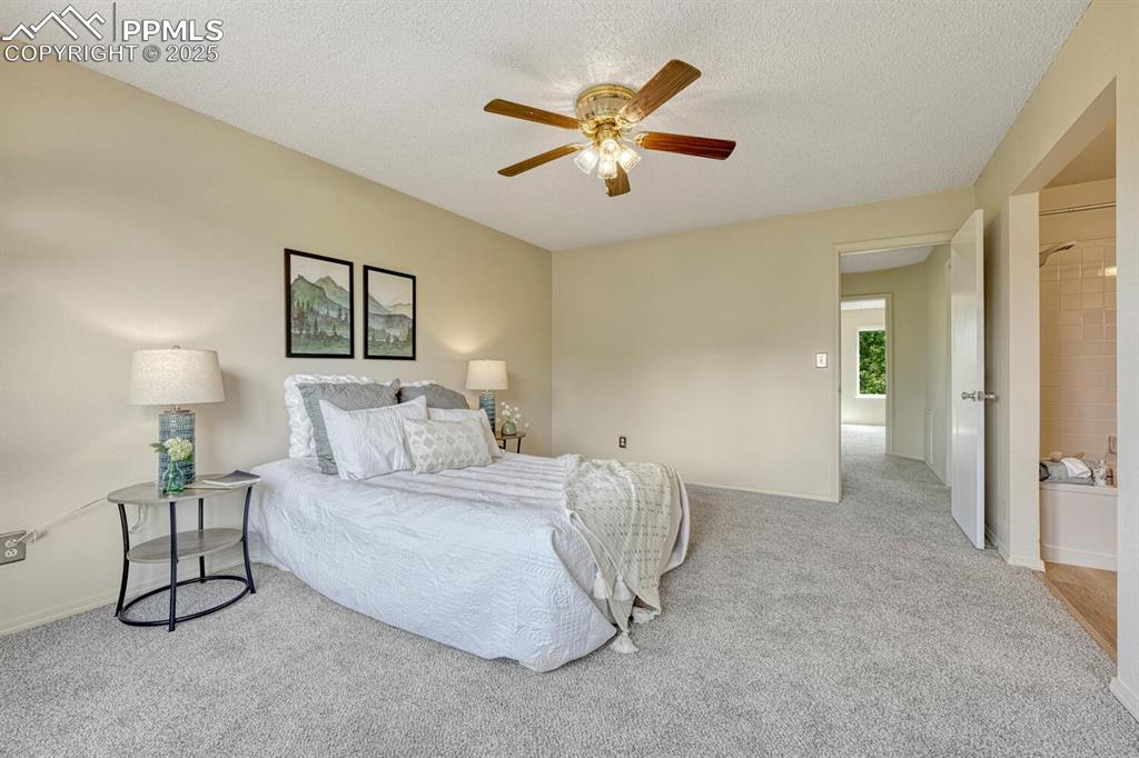Image 22 of 40: Upper Level Primary Bedroom with new carpet, a lighted ceiling fan, walk in