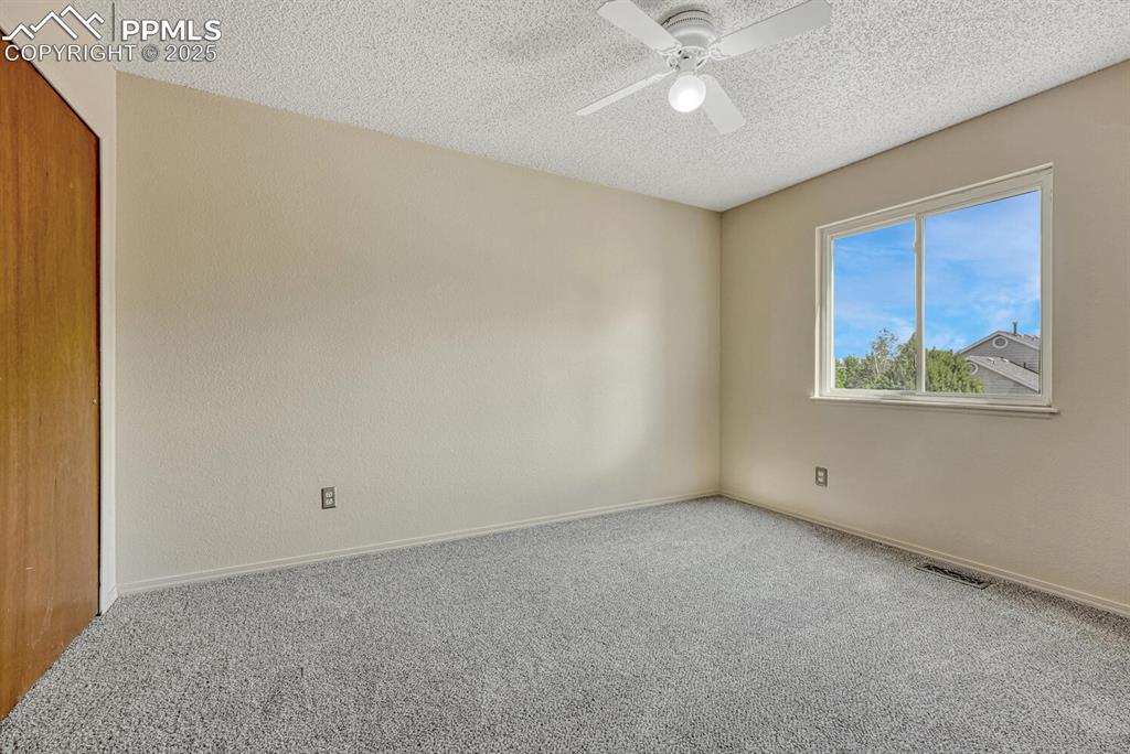Image 29 of 40: Upper Level Bedroom #3 has new carpet and a lighted ceiling fan.