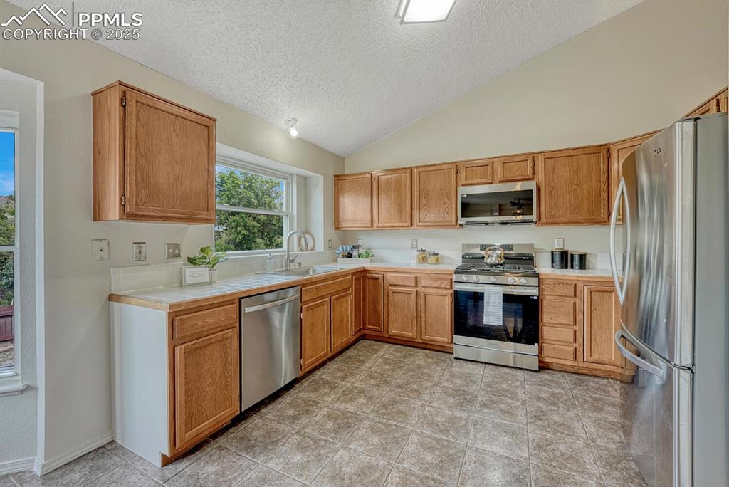 Image 7 of 40: The Kitchen boasts a tile floor, wood cabinets, tile countertops, a pantry,