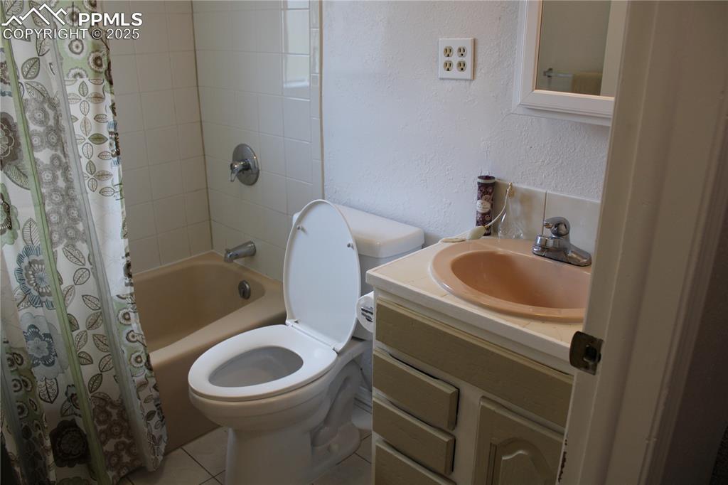 Image 12 of 35: Full bath with shower / tub combo with curtain, a textured wall, vanity, an