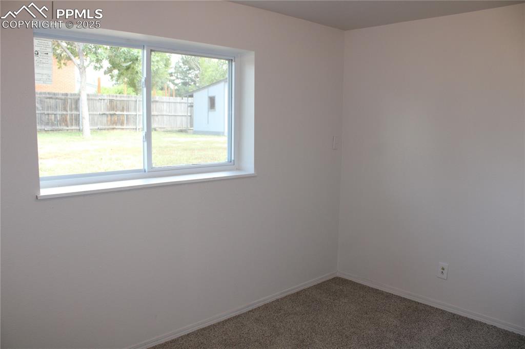 Image 15 of 35: Carpeted bedroom with baseboards with window out to back yard.