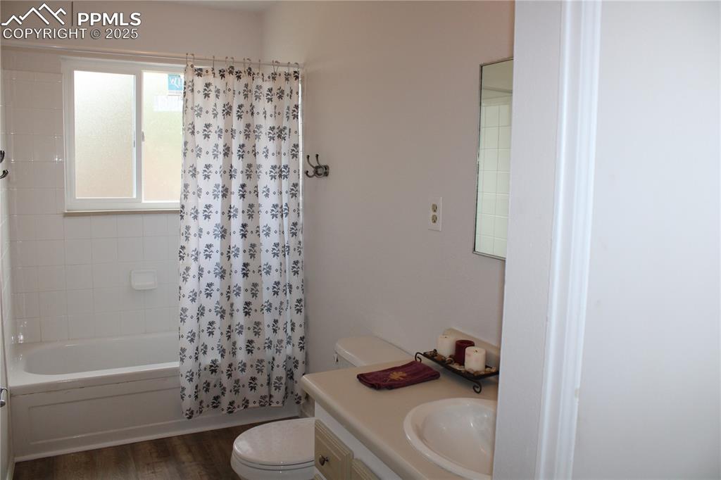 Image 17 of 35: Full bathroom featuring shower / tub combo, vanity, and dark wood-style flo