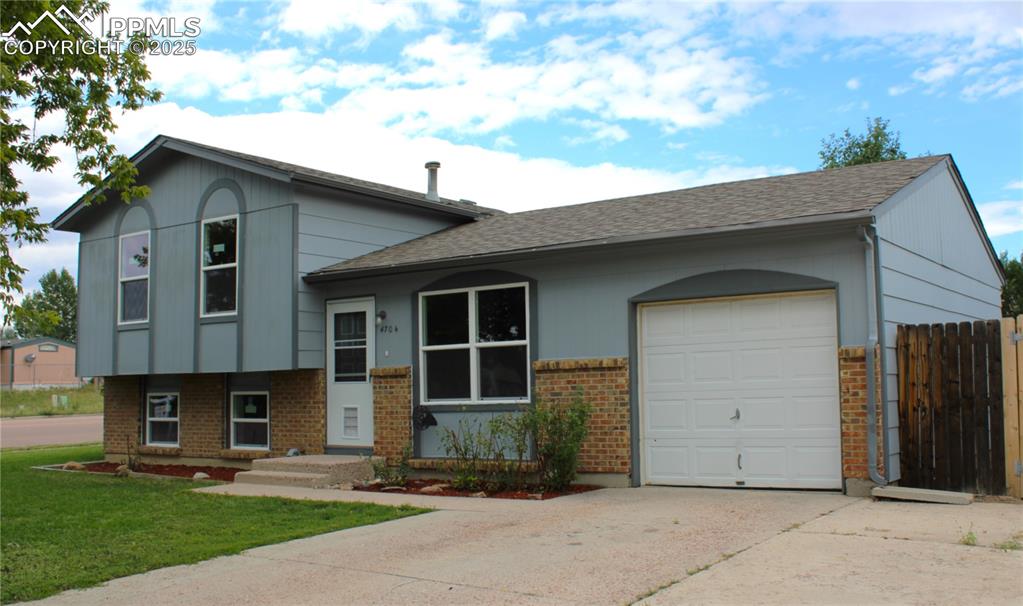 Image 34 of 35: Split level home featuring an attached garage, brick siding, roof with shin