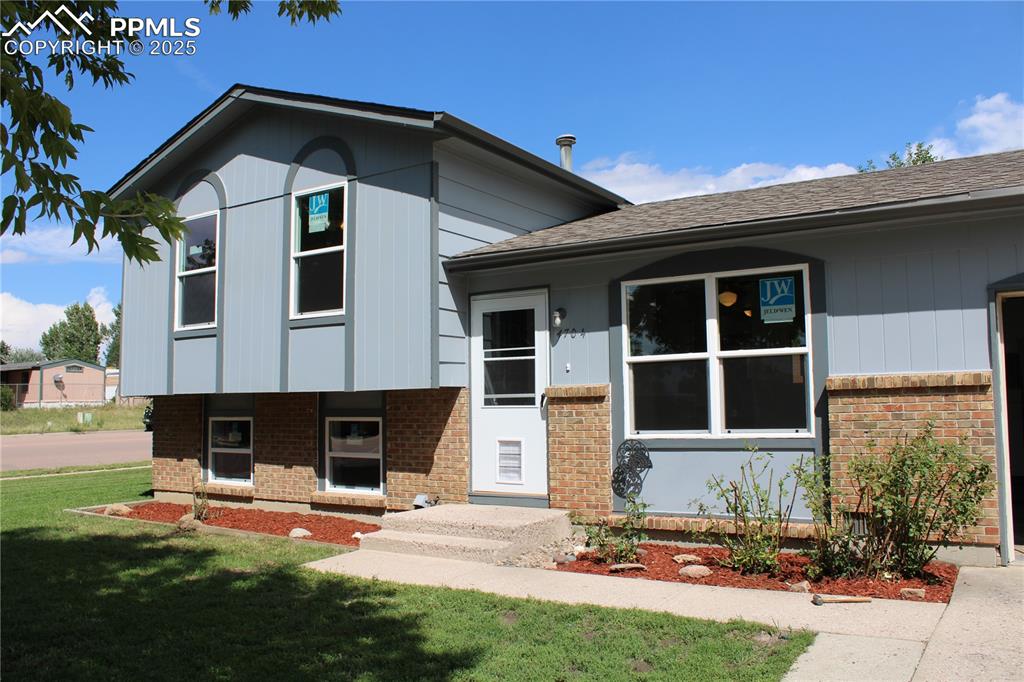 Image 35 of 35: Tri-level home featuring a front lawn, a shingled roof, and brick siding