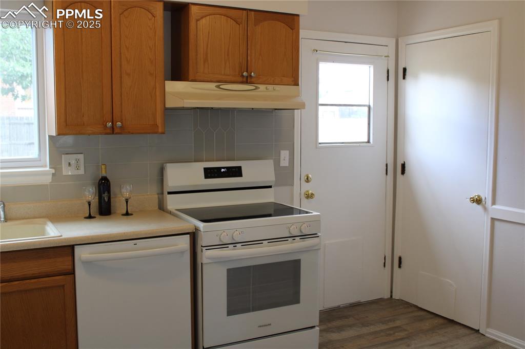 Image 8 of 35: Kitchen featuring brown cabinets, white appliances, and light countertops