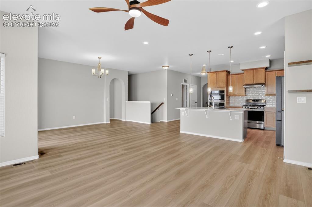 Image 10 of 49: Open-concept living space featuring wood-finish flooring, recessed lighting