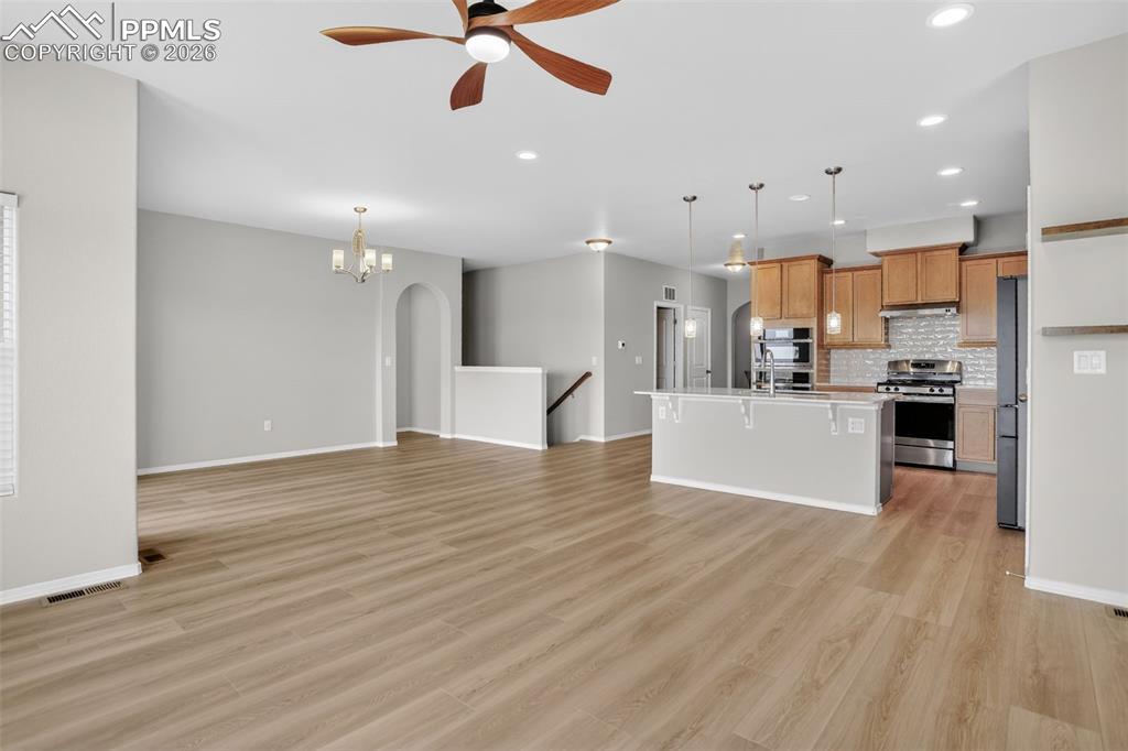 Image 11 of 44: Spacious living area featuring wood-finish flooring, a stone-faced fireplac