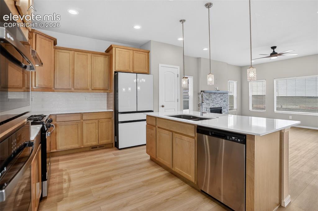 Image 11 of 49: Open-concept kitchen featuring light wood-finish cabinetry, a white subway
