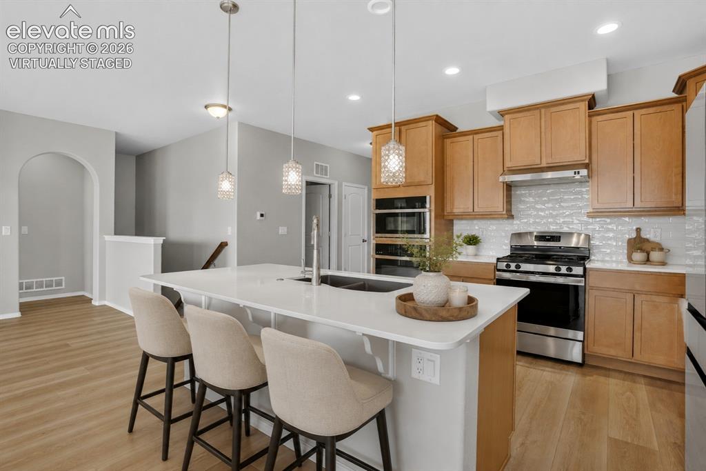Image 12 of 49: Open-concept kitchen featuring light wood-finish flooring, a white island w