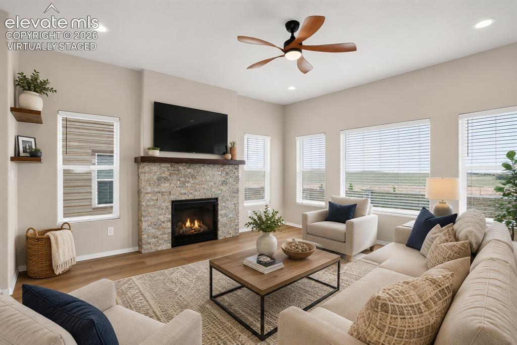 Image 14 of 49: Living area featuring a stone-clad fireplace with a wood mantel, wood-finis