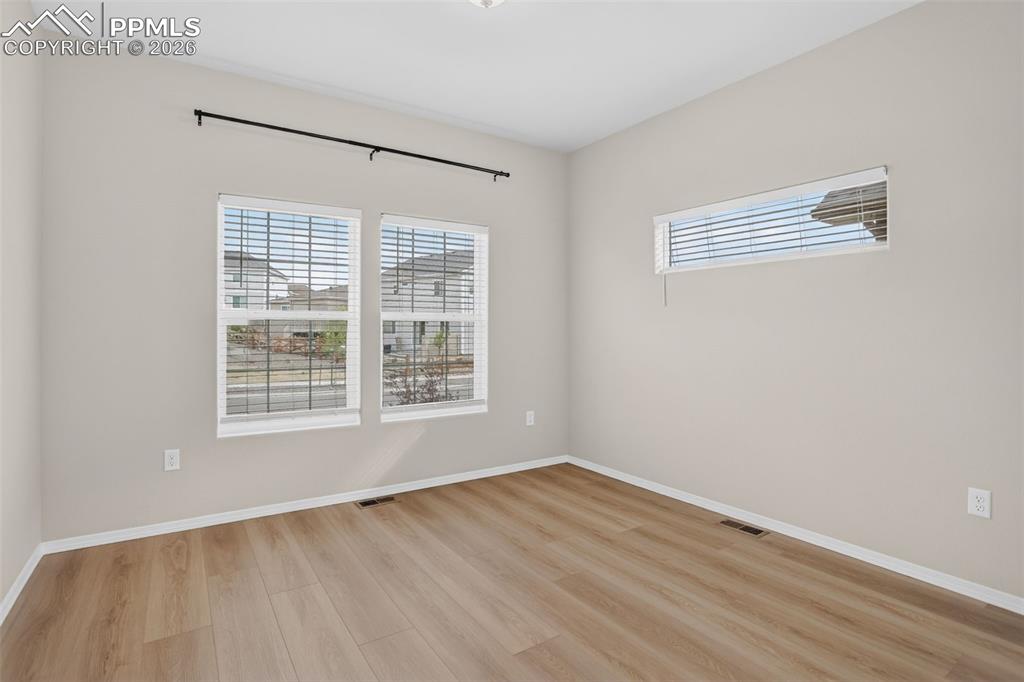 Image 15 of 44: Spacious living area featuring wood-finish flooring, a stone-clad fireplace