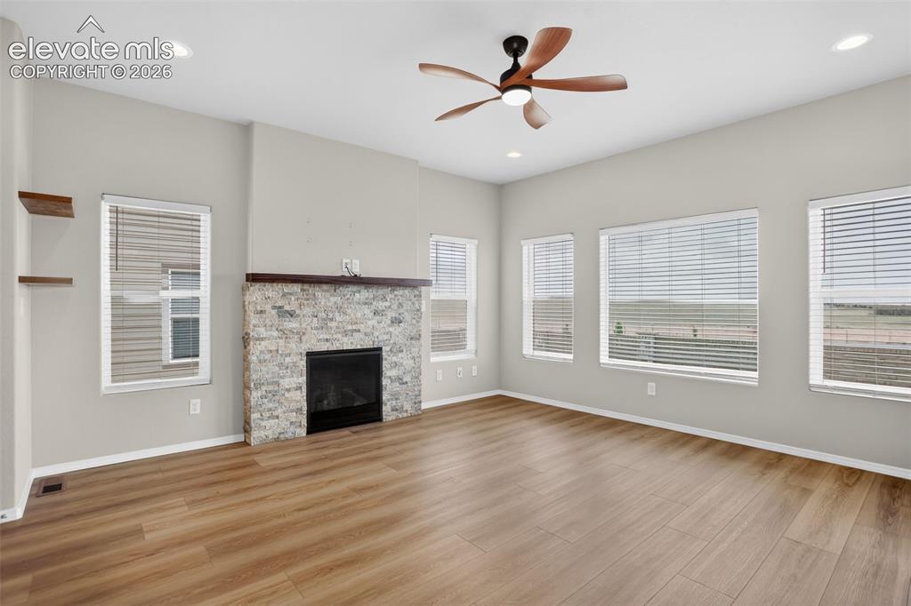 Image 15 of 49: Spacious living area featuring wood-finish flooring, a stone-faced fireplac