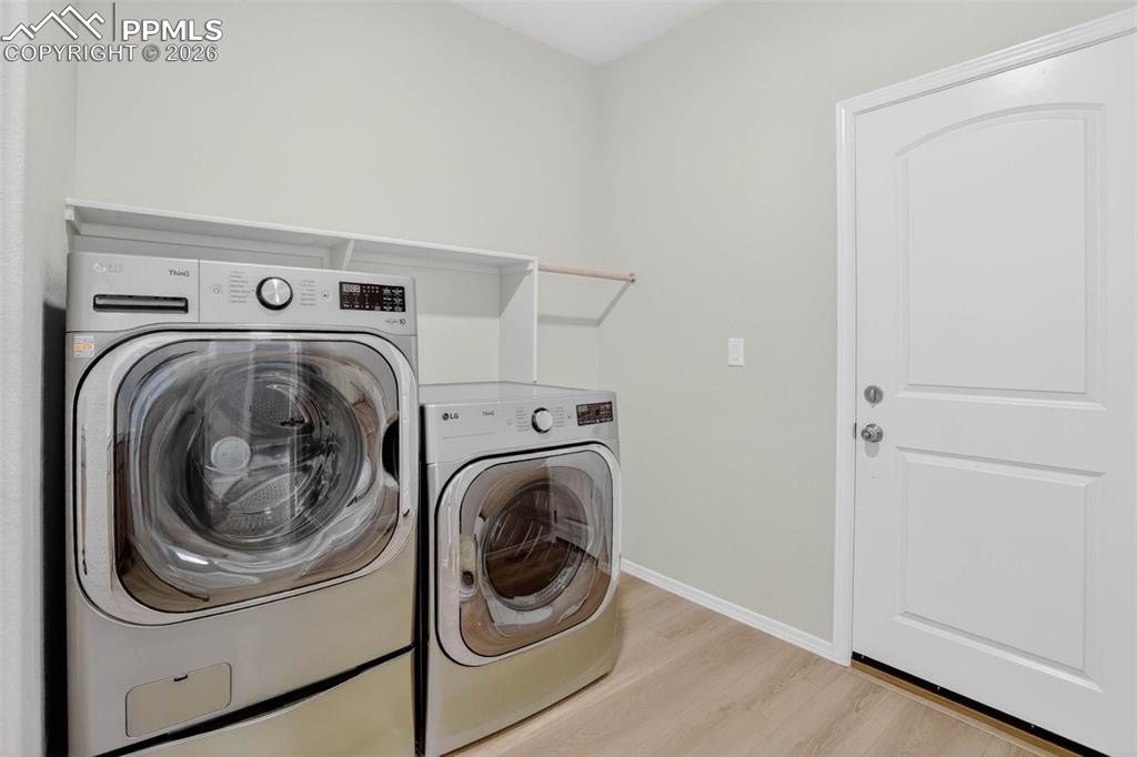 Image 17 of 44: Room featuring wood-finish flooring, two large windows with blinds, an addi