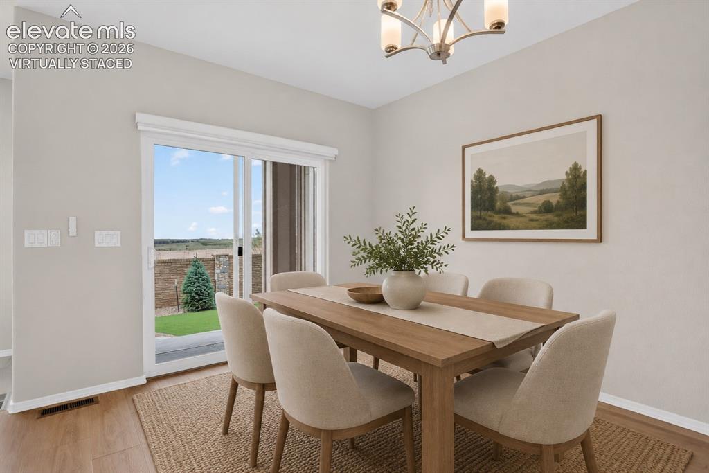 Image 17 of 49: Dining area featuring wood-finish flooring and a contemporary chandelier -