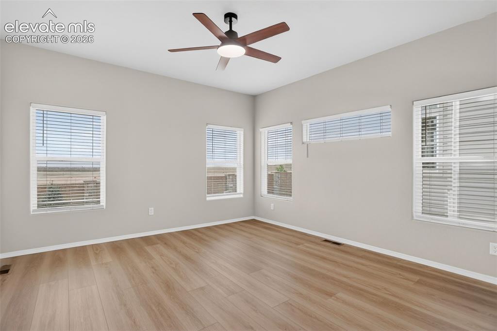 Image 22 of 49: Spacious room featuring wood-finish flooring, a contemporary ceiling fan wi