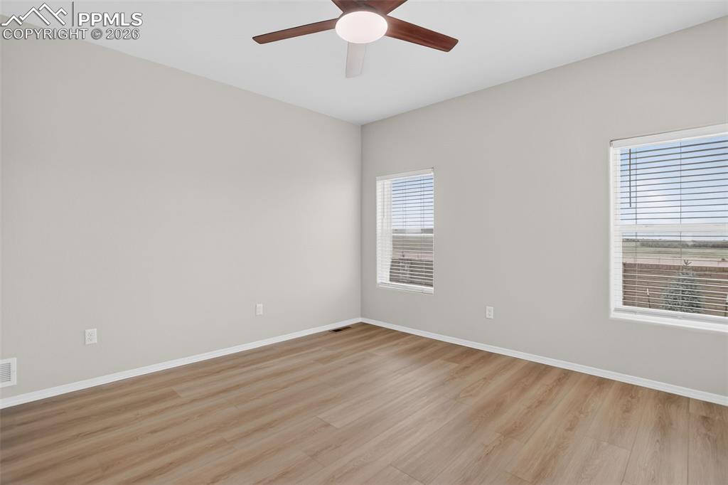 Image 24 of 44: Spacious room featuring wood-finish flooring, a contemporary ceiling fan, a