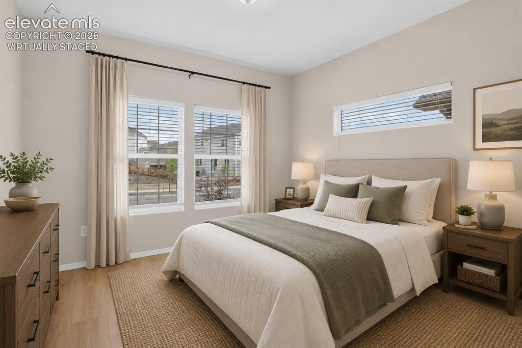 Image 3 of 49: Bedroom featuring wood-finish flooring, a neutral upholstered headboard, du