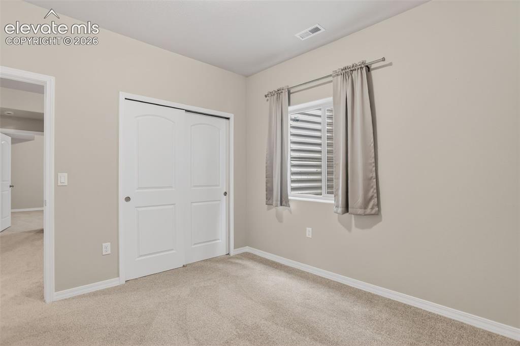 Image 35 of 49: Carpeted room featuring light beige walls, a built-in closet with white bi-