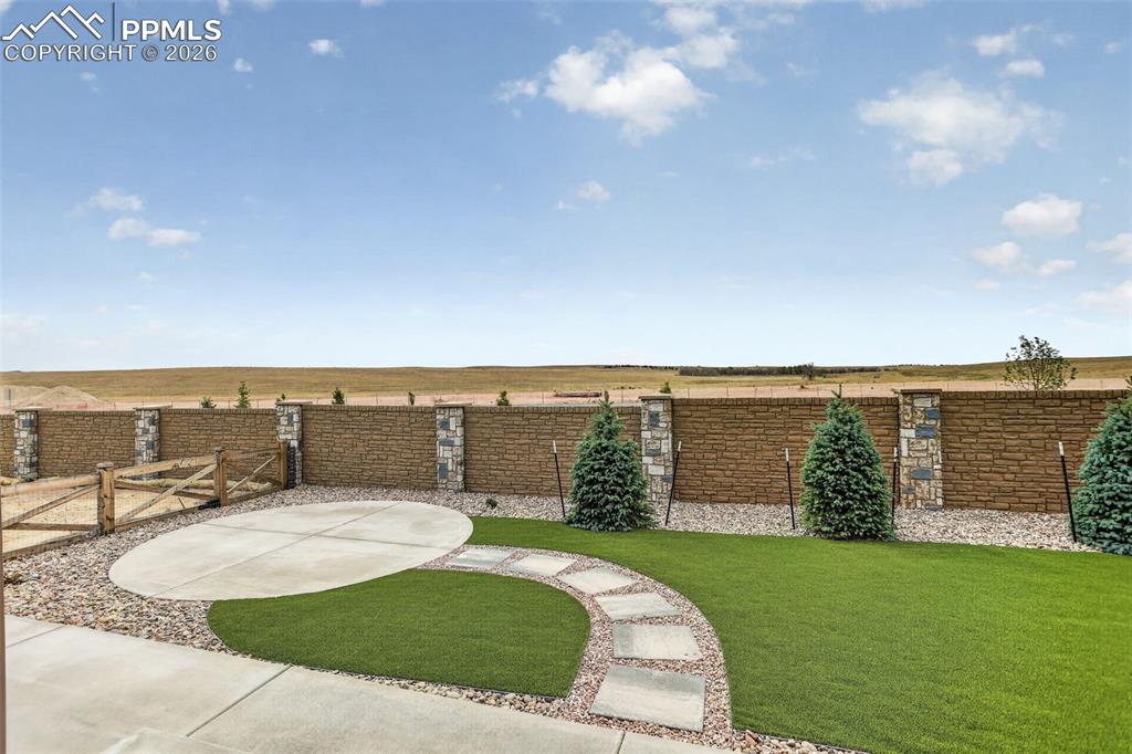 Image 38 of 44: Backyard featuring artificial turf, decorative gravel, and a concrete patio