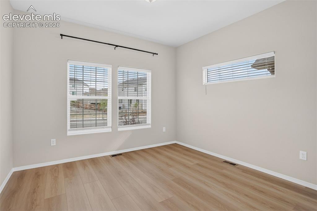 Image 4 of 49: Room featuring wood-finish flooring, two large windows with blinds, an addi