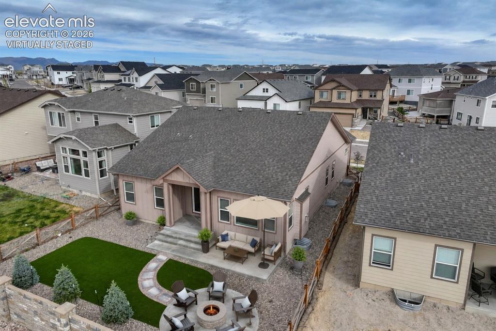 Image 42 of 49: Expansive backyard featuring a stone patio, fire pit area, and artificial t