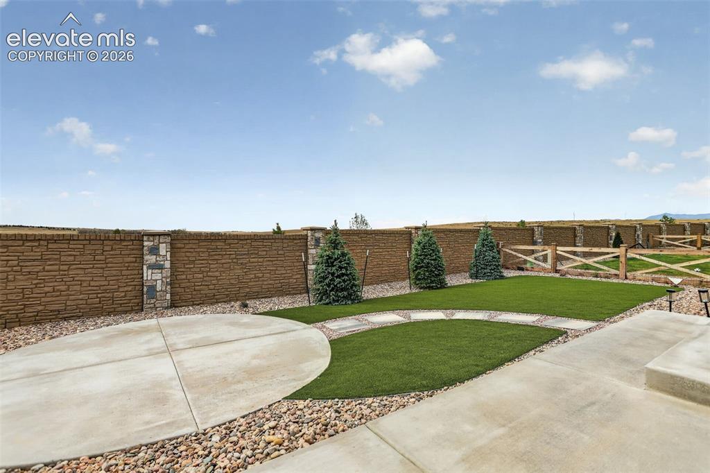 Image 46 of 49: Expansive outdoor area featuring a patterned concrete patio, decorative gra