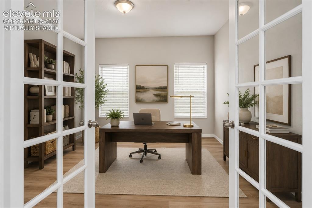 Image 7 of 49: French doors opening to a dedicated room with three windows, wood-finish fl