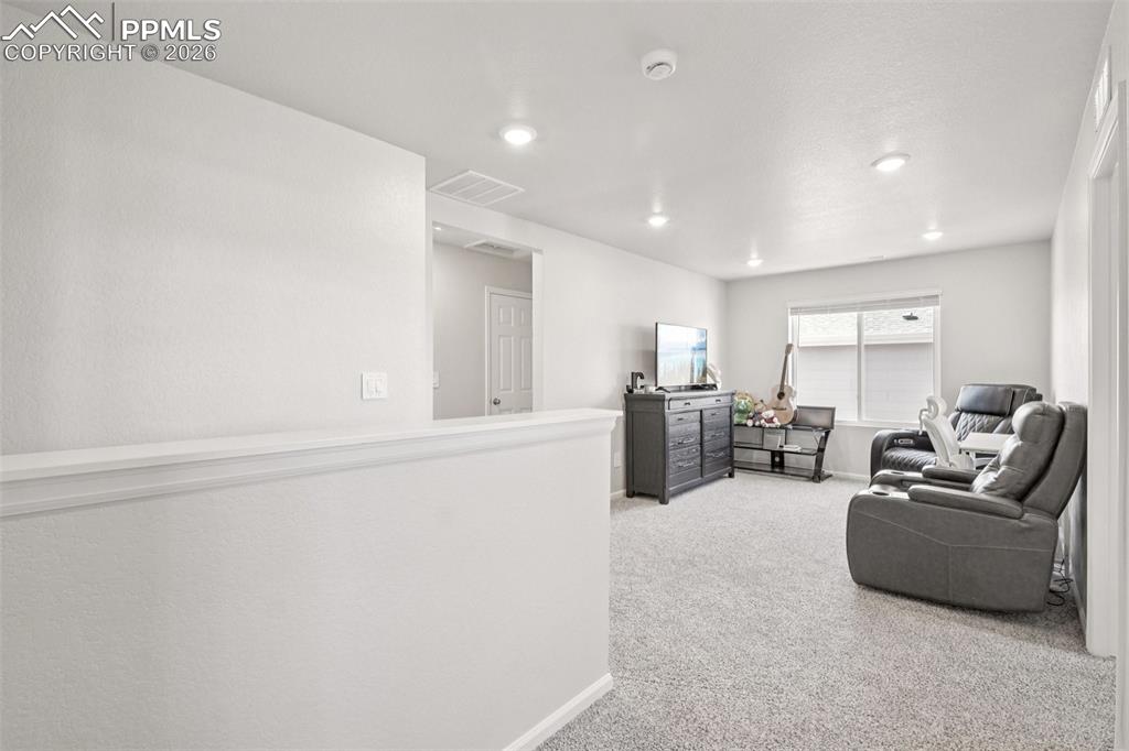 Image 17 of 34: Living area featuring light carpet and recessed lighting