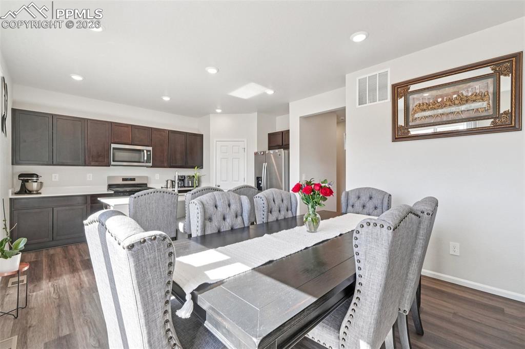 Image 9 of 34: Dining room featuring dark wood-style floors and recessed lighting