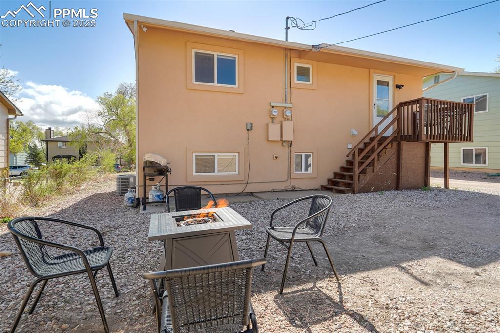 Image 15 of 25: Back of property with a patio area, stucco siding, stairway, and a fire pit