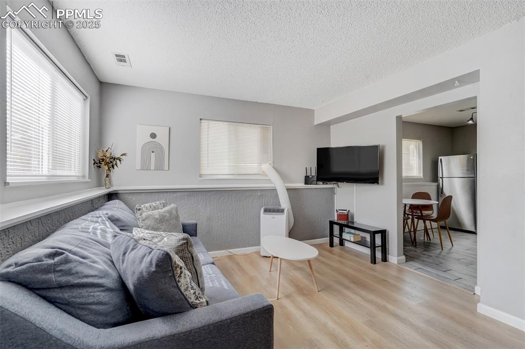 Image 19 of 25: Living room featuring light wood-type flooring and a textured ceiling