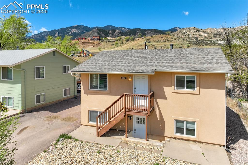 Image 2 of 25: Back of house featuring stucco siding, a shingled roof, and a mountain view