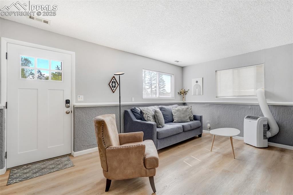 Image 20 of 25: Living room with a textured ceiling and light wood finished floors