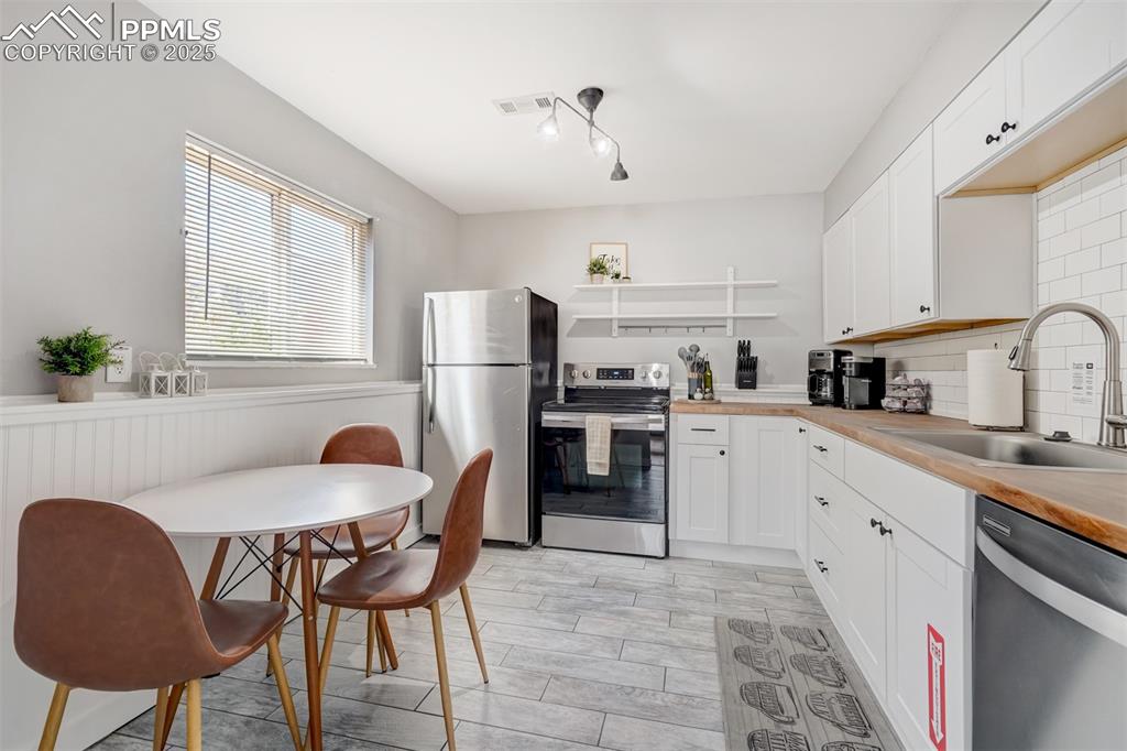 Image 21 of 25: Kitchen featuring appliances with stainless steel finishes, backsplash, whi