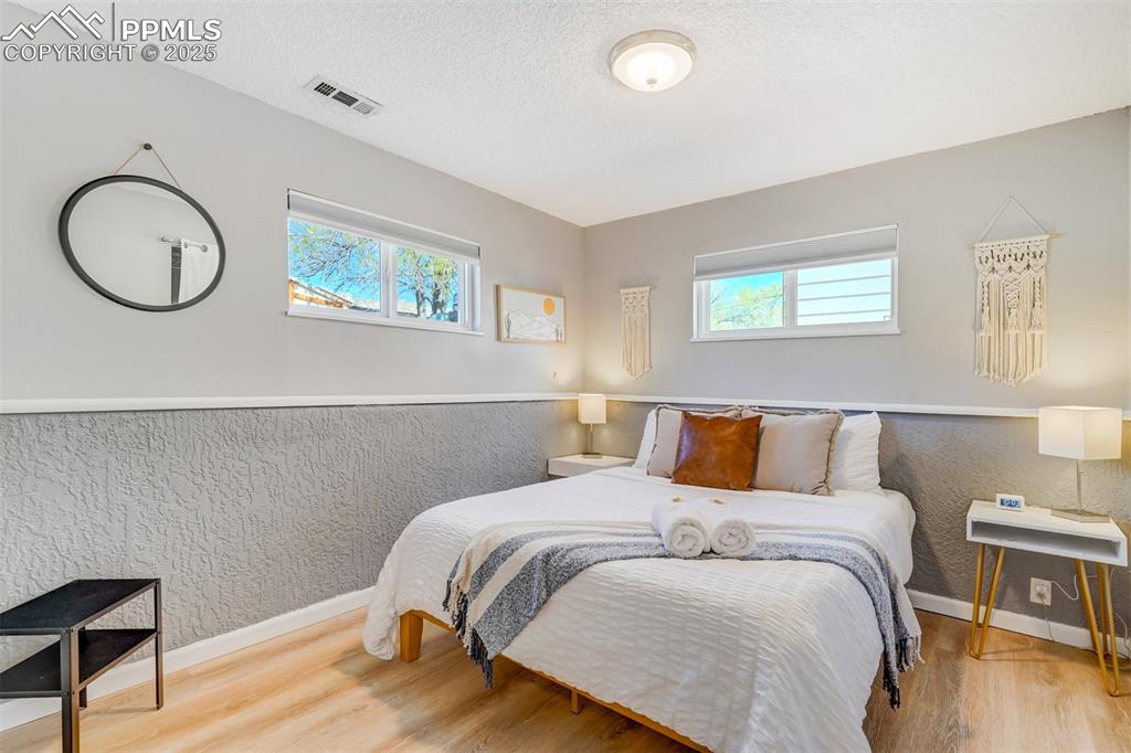 Image 22 of 25: Bedroom with light wood-style floors and a textured ceiling