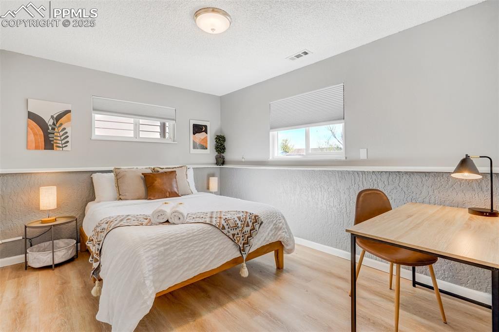 Image 23 of 25: Bedroom with a textured ceiling, light wood finished floors, and a textured