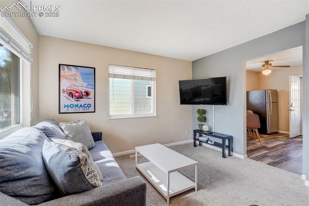 Image 5 of 25: Carpeted living room featuring plenty of natural light and a ceiling fan