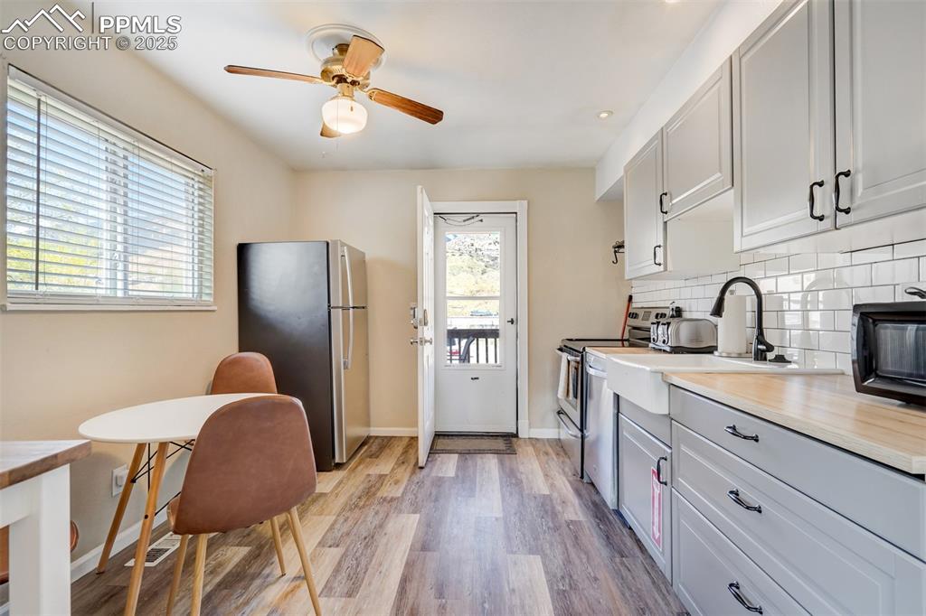 Image 7 of 25: Kitchen with stainless steel appliances, light wood-type flooring, white ca