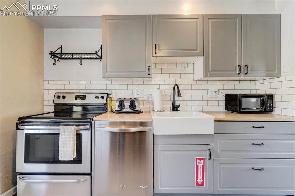 Image 8 of 25: Kitchen with appliances with stainless steel finishes, decorative backsplas