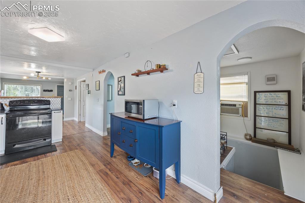Image 14 of 36: Kitchen featuring arched walkways, a textured ceiling, black range with ele
