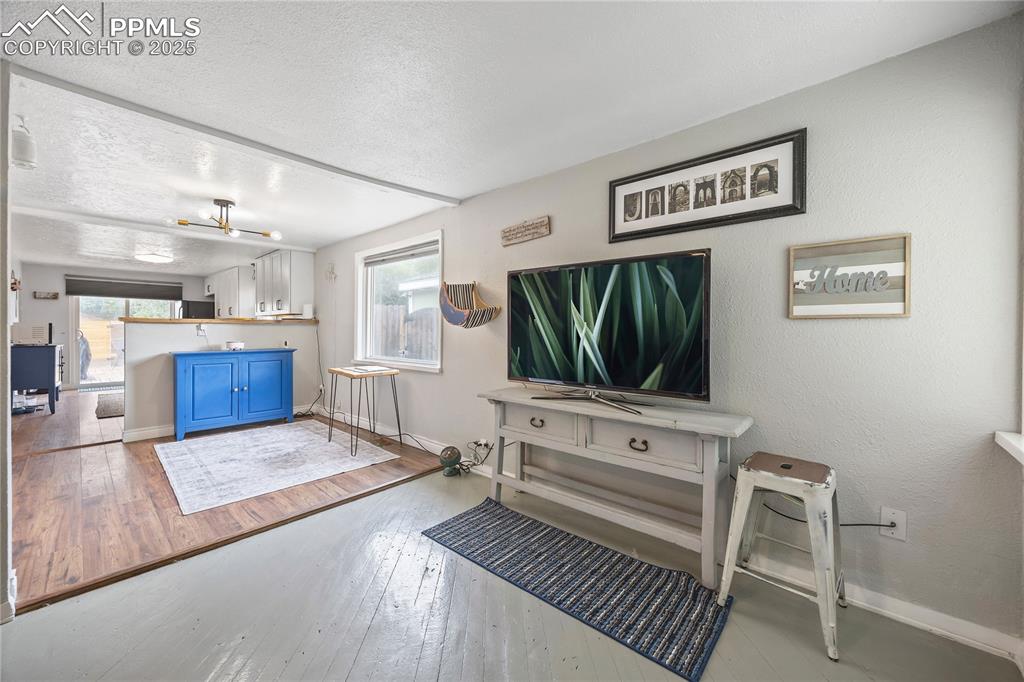 Image 15 of 36: Living room with wood-type flooring, a textured ceiling, baseboards, and a