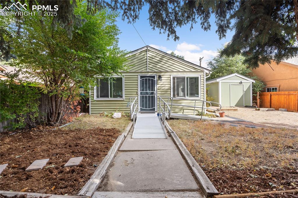 Image 2 of 36: Bungalow with a fenced backyard, a storage unit, and an outbuilding