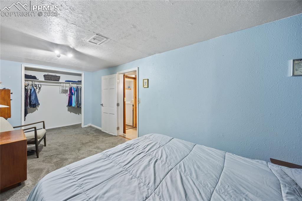 Image 30 of 36: Carpeted bedroom featuring a closet, visible vents, a textured wall, a text