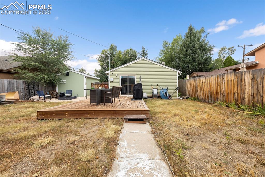 Image 33 of 36: Back of house featuring a lawn, fence, and a wooden deck