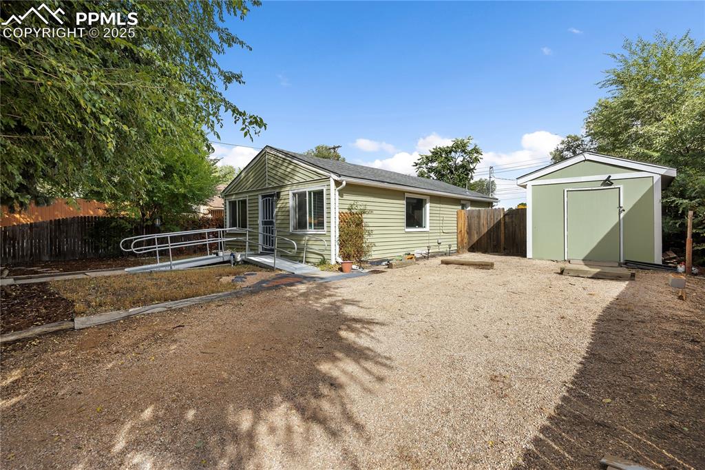 Image 36 of 36: View of front facade with a storage unit, an outdoor structure, and fence