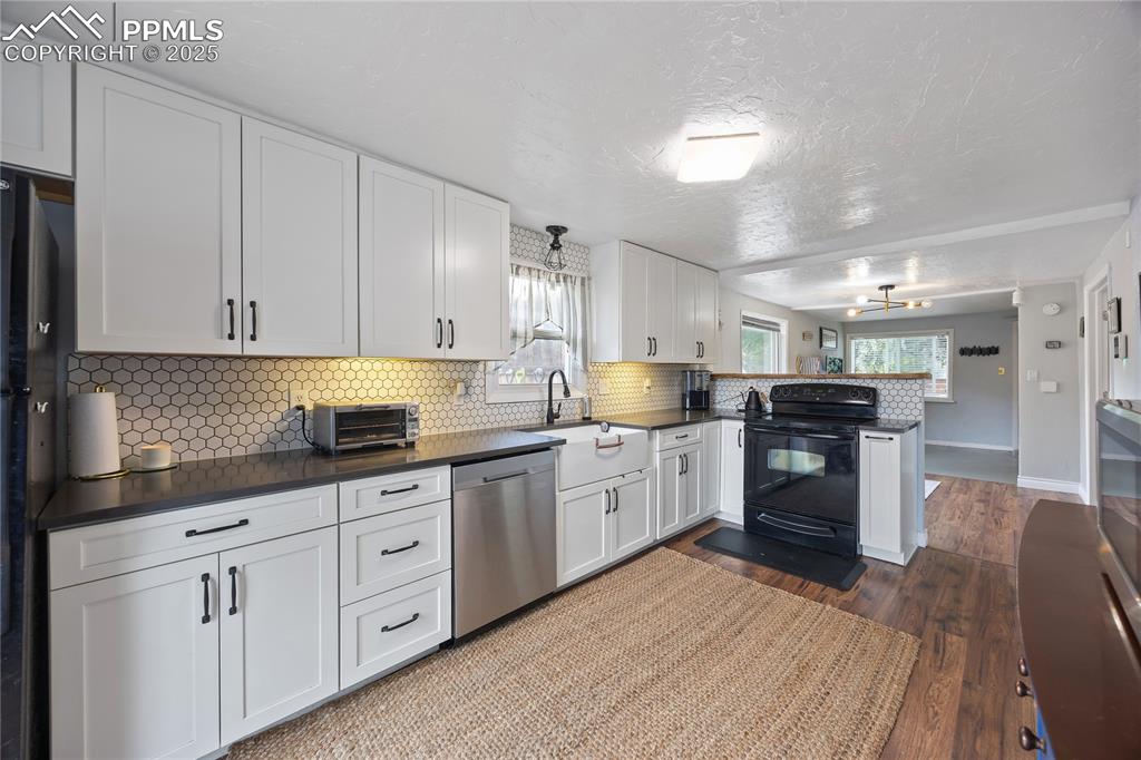 Image 5 of 36: Kitchen featuring dark countertops, a sink, a peninsula, and black applianc