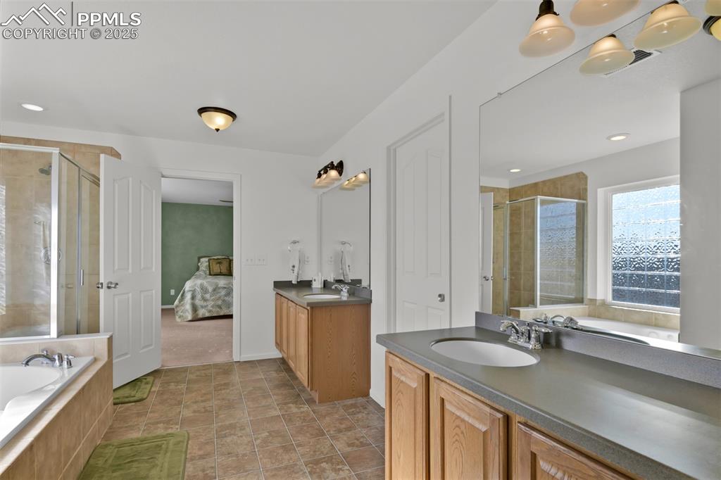 Image 23 of 50: Bathroom featuring a bath, two vanities, a stall shower, and recessed light